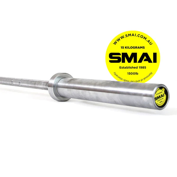 A close-up of a metallic barbell with a yellow circular label highlights the 105kg HD Bumper Plate Set Inc 15kg Barbell. The label reads "Sale Item, established in 1985, 15 kilograms, 1500 lb" and features the website "www.smai.com.au." It's ideal for serious Olympic lifting enthusiasts.