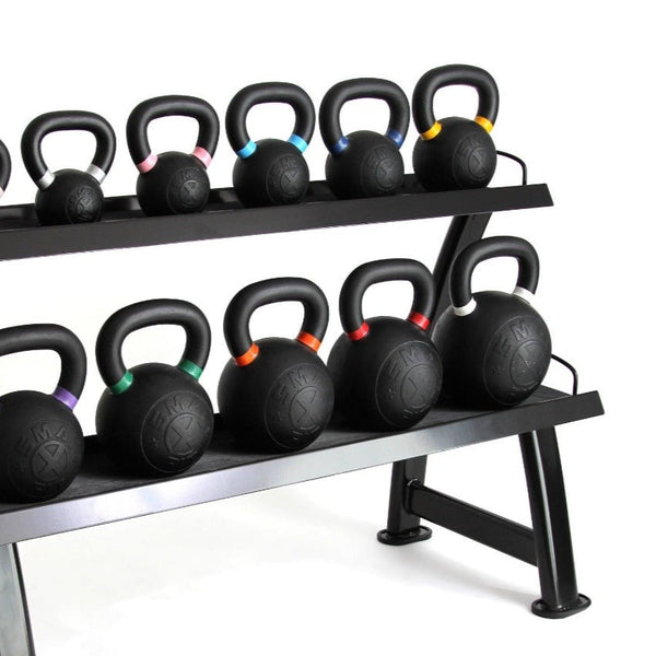 A set of black kettlebells with colored bands on their handles are neatly arranged on the SMAI Kettle Bell Storage Rack - 2 Layer. The high-gauge steel rack, featuring rubber-lined shelves, holds various sizes of kettlebells, indicating different weights.