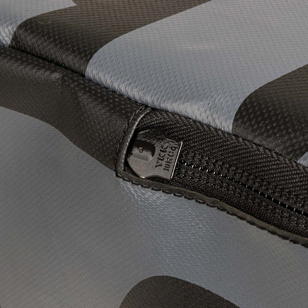 Close-up image of a zipper on the fabric surface of a black and gray Plyometric Box - WOD Pro. The zipper is partially open, revealing a slider with text engraving. The textured material, reminiscent of competition-grade boxes from SMAI, appears both durable and robust.