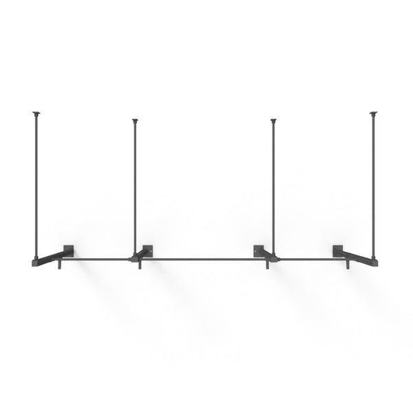 The Wall Mounted Rig - 2 Squat Cell with Bridge - X-Frame by No Sync To Channel Engine is a minimalist shelving unit made of black steel tubing. It features a modular design with three support brackets, mounted on a white wall. This product includes four vertical bars connected to a horizontal bar, making it ideal for displaying items.