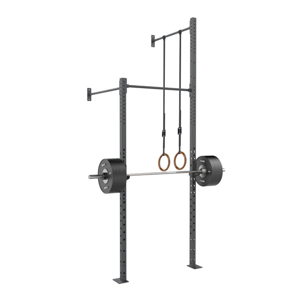 The Wall Mounted Rig - 1 Squat Cell with Bridge - X-Frame by No Sync To Channel Engine can support a loaded barbell and includes gymnastic rings hanging from the top bar. This piece of commercial equipment is designed to be modular, featuring durable steel racks with numerous adjustment holes and a pull-up bar across the top.